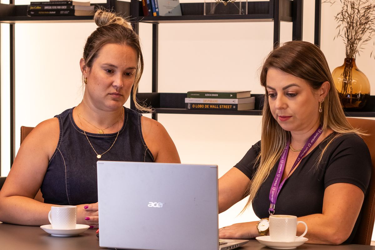 Duas profissionais conversando diante de um notebook